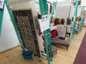 Women at looms weaving rugs 