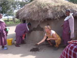 Maasai women show visitor how mud hut is repaired using elephant dung and water.